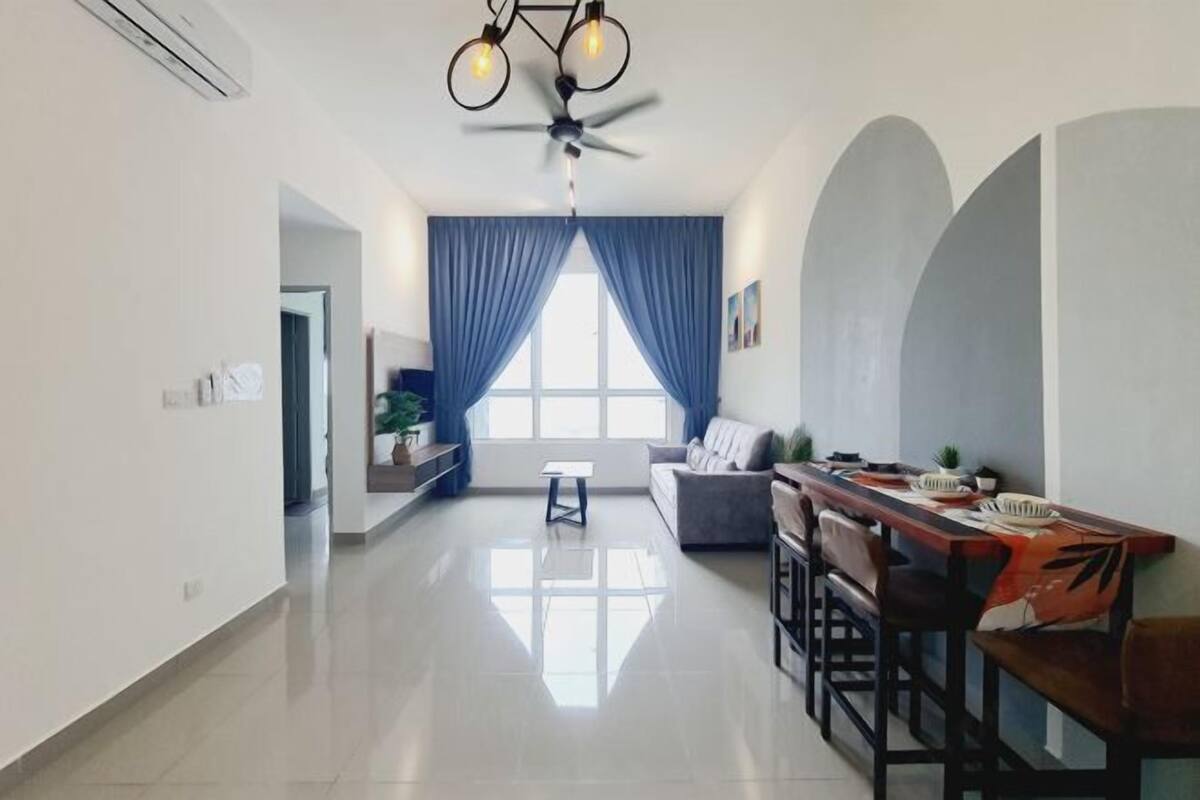 A modern living room with a dining area, a ceiling fan, and a large window with blue curtains.