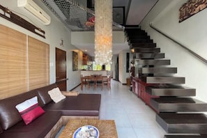 A modern living room with a sofa, coffee table, and a staircase leading to an upper level. - 3 bedroom Penthouse at Asiana Villas in Boracay 5 minutes walk to White Beach (Boracay Island)