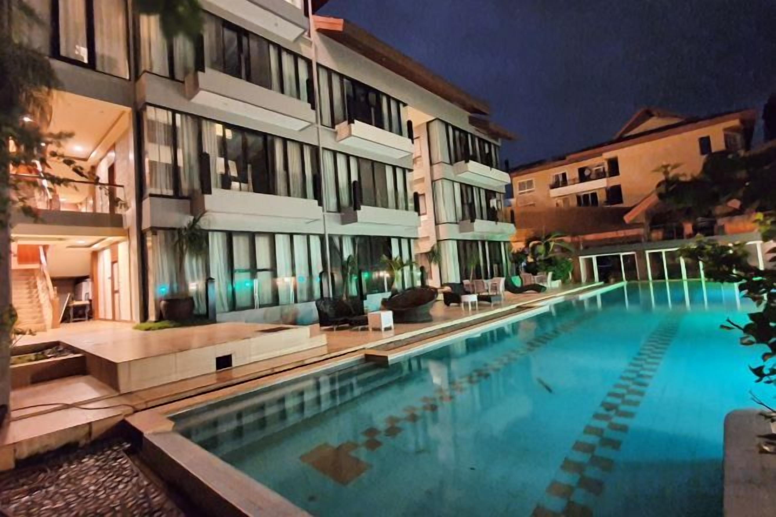 Un hotel moderno con piscina, zona de estar al aire libre y una entrada bien iluminada.
