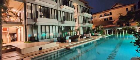 Un hotel moderno con piscina, zona de estar al aire libre y una entrada bien iluminada.