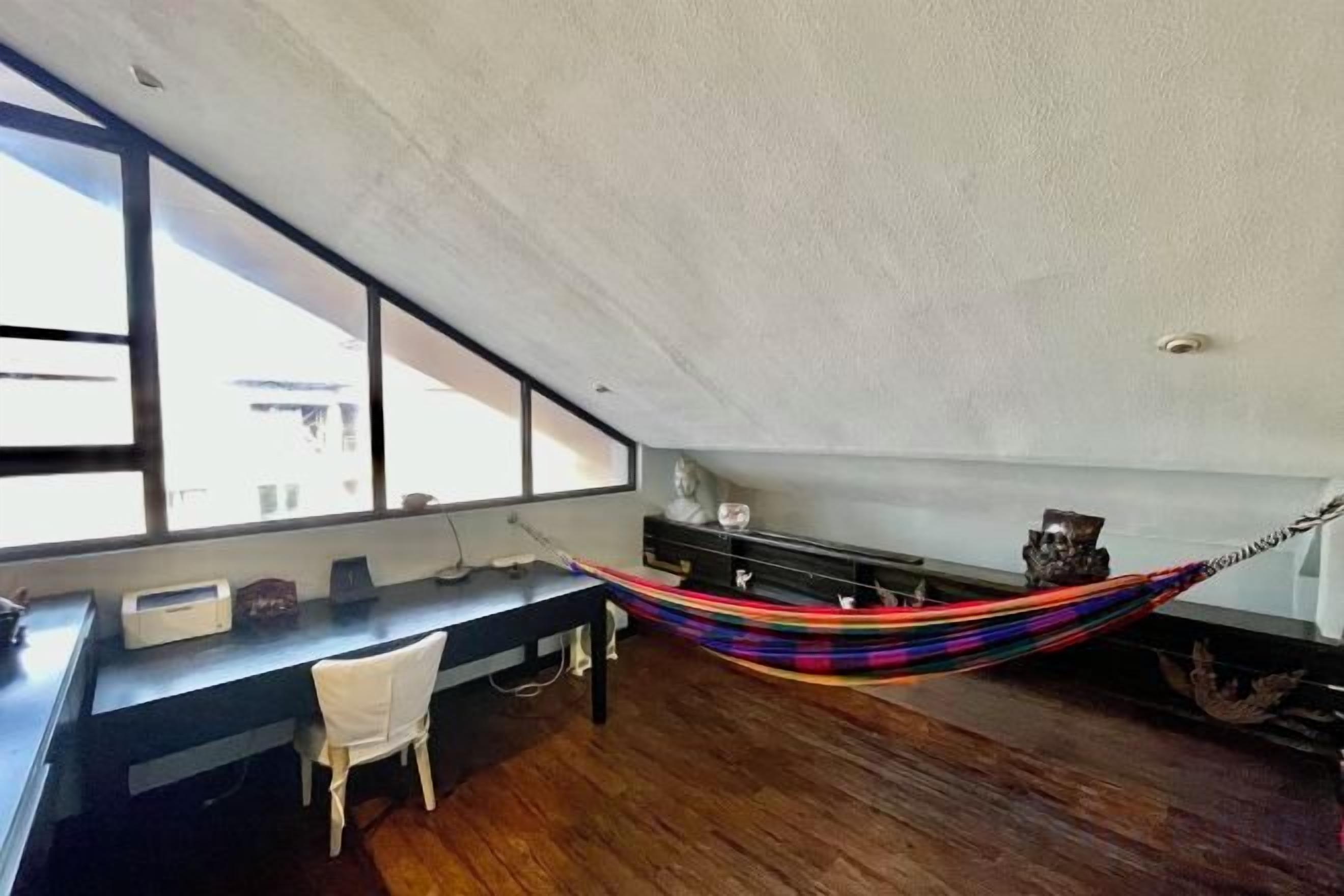 Una habitación con escritorio, silla y una hamaca.