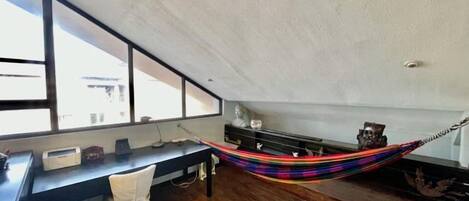 Una habitación con escritorio, silla y una hamaca.