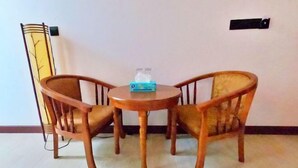 A small round table with two wooden chairs, a tissue box, and a wall-mounted light fixture. - Blue Coral Vashafaru Maldives (Vashafaru)