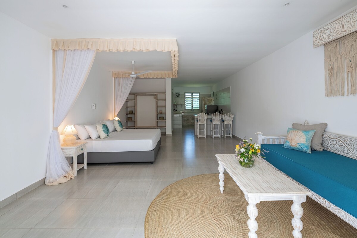 A modern living room with a bed, sofa, and dining area.