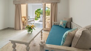 Una habitación con sofá, una mesa con un florero y vistas a un espacio exterior con patio y sillas.