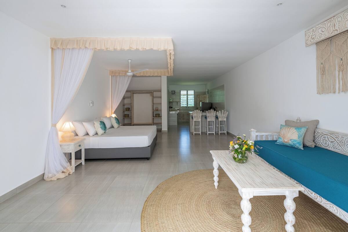 A modern living room with a bed, sofa, and dining area.