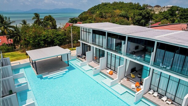 A modern multi-story building with a large swimming pool, outdoor seating, and a view of the ocean. - Pool Access Massive Townhouse (Bophut)