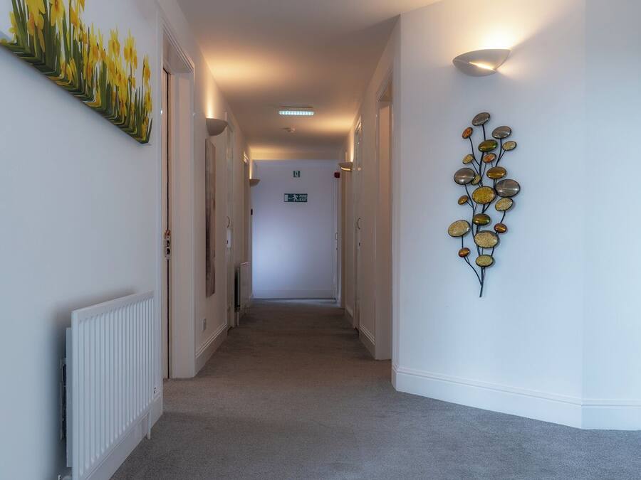 A hallway with white walls, a radiator on the left, and a decorative wall piece on the right.