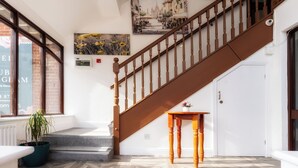 Un escalier avec des balustrades en bois menant à un palier où se trouvent une petite table et une plante en pot.