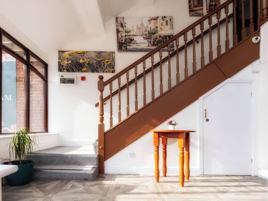 A staircase with wooden balusters leading to a landing with a small table and a potted plant.