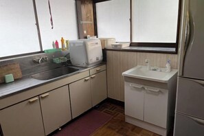 A compact kitchen with a sink, countertop, and a small refrigerator. - Bullfighting and Nishikigoi Traditional Culture Center (Ojiya)