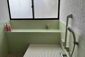 A bathroom with a window, a shelf with toiletries, and a radiator. - Bullfighting and Nishikigoi Traditional Culture Center (Ojiya)