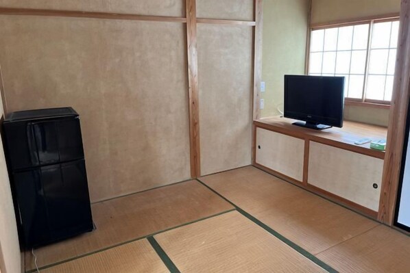A room with tatami flooring, a television on a low stand, and a refrigerator. - Bullfighting and Nishikigoi Traditional Culture Center (Ojiya)