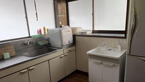 Cocina compacta con lavamanos, encimera y un refrigerador pequeño.