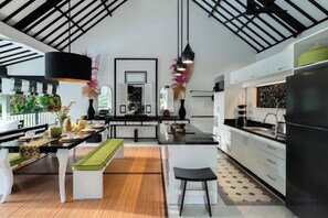 A modern kitchen with a central island, black appliances, and a wooden floor. - Villa Lepak by the River (Bali)