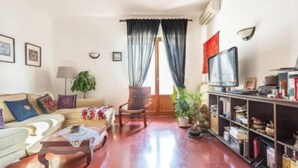 Un salon comprenant un canapé, un fauteuil, une télévision et des étagères remplies de livres et d’objets décoratifs.