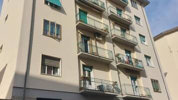 Un edificio residencial de varios pisos con balcones, ventanas con contraventanas y fachada de piedra.