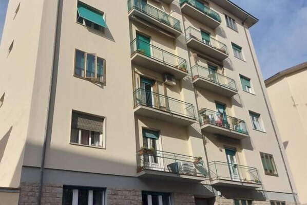 Un edificio residencial de varios pisos con balcones, ventanas con contraventanas y fachada de piedra.