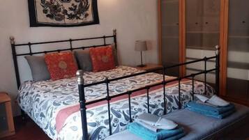 A bed with a metal frame, a bedside table, and a wall-mounted lamp.