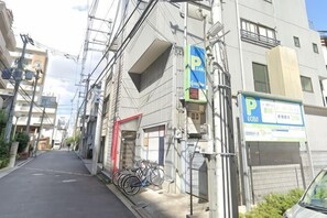 A narrow urban street with buildings, a parking sign, and bicycles. - Osaka Tamatsukuri (Osaka)