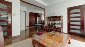A spacious room with a wooden floor, a glass-top table, and a wooden cabinet with glass doors. - Osaka Tamatsukuri (Osaka)