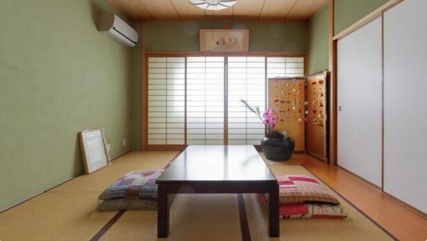 A traditional Japanese room with tatami flooring, a low table, sliding shoji doors, and a ceiling fan. - Osaka Tamatsukuri (Osaka)