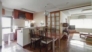 A modern kitchen with a dining area, wooden cabinets, and a large window. - Osaka Tamatsukuri (Osaka)