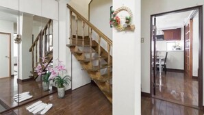 A staircase with wooden steps and a handrail, leading to a room with white walls and a mirror reflecting the interior. - Osaka Tamatsukuri (Osaka)