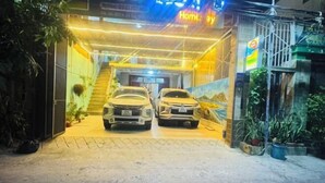 A garage entrance with two cars parked inside, a staircase leading to the upper level, and potted plants outside. - Sea Home Homestay (Phan Thiet)