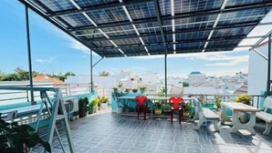 A rooftop terrace with solar panels, outdoor seating, and potted plants. - Sea Home Homestay (Phan Thiet)
