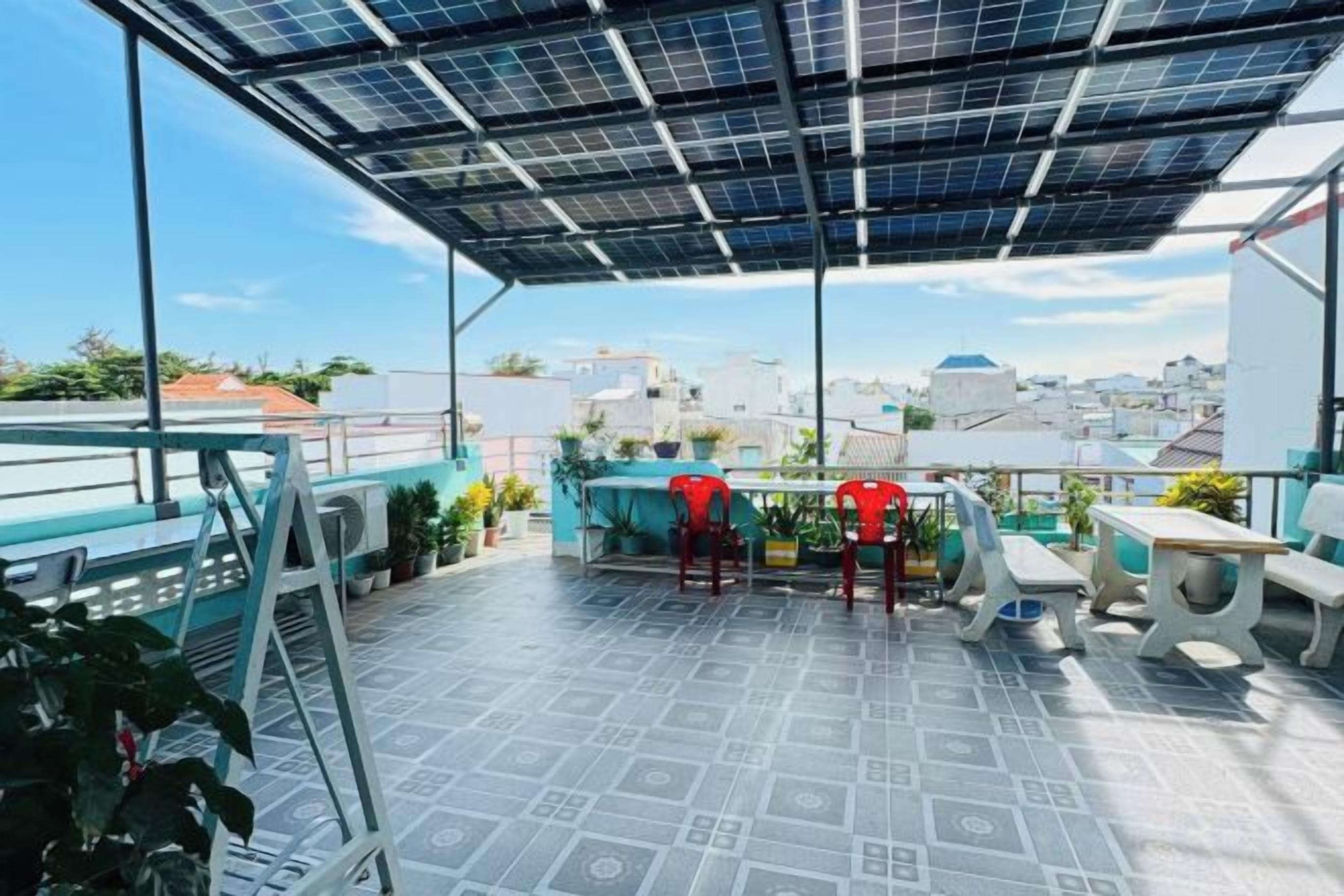 A rooftop terrace with a solar panel roof, outdoor seating, and a city view.
