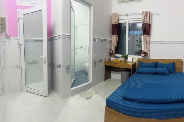 A bedroom with a bed, a desk, a mirror, and a wardrobe.