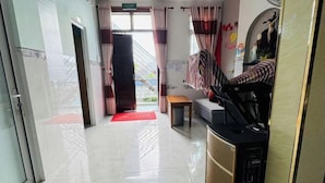 A hotel lobby with a reception desk, a sofa, a small table, and a red mat on the floor. - Sea Home Homestay (Phan Thiet)