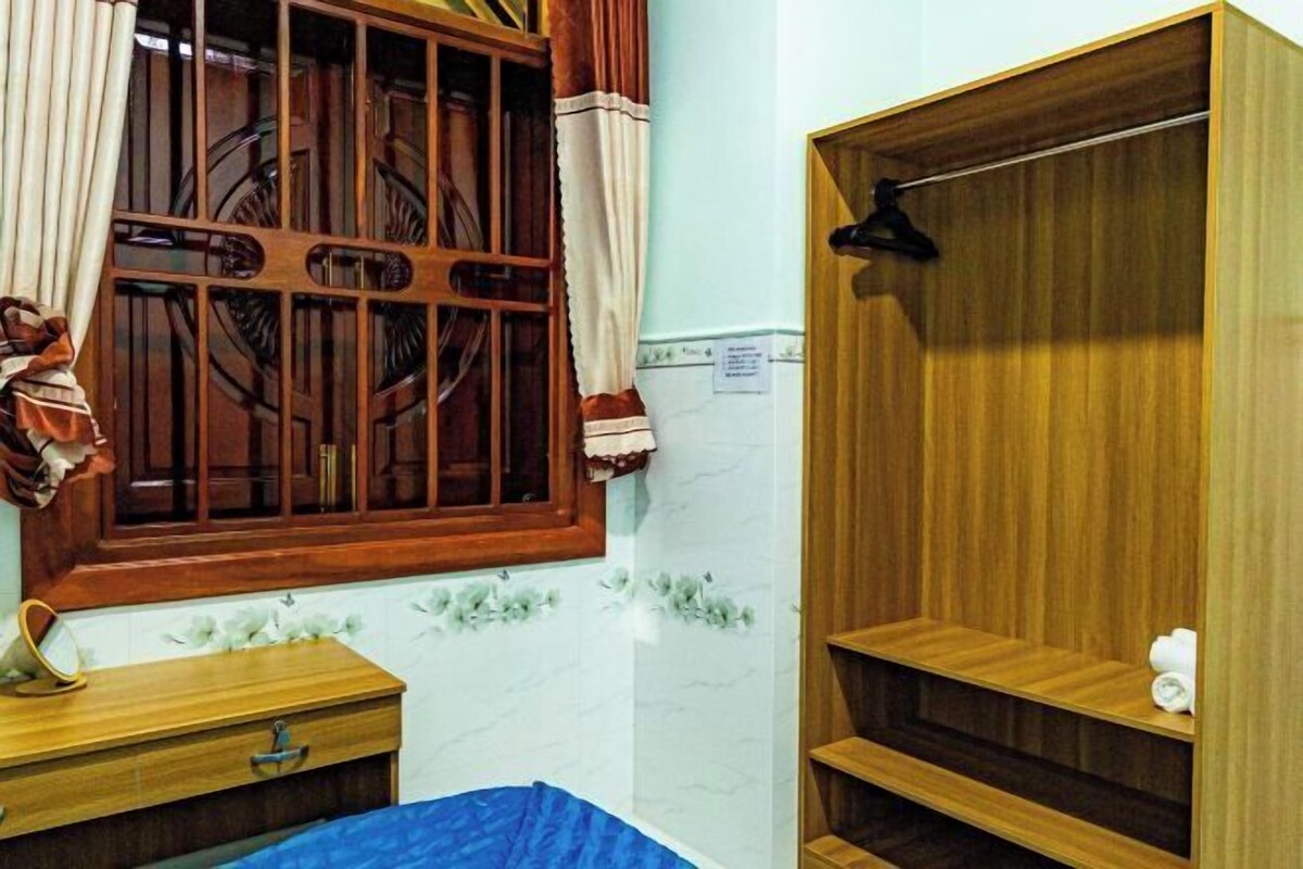 A room with a wooden wardrobe, a wooden desk, and a window with curtains.