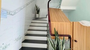 A staircase with black steps, a wooden handrail, and a potted plant on the landing. - Sea Home Homestay (Phan Thiet)