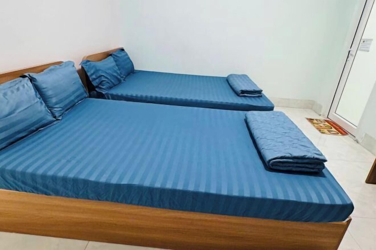 A room with two single beds, each with blue bedding and pillows.