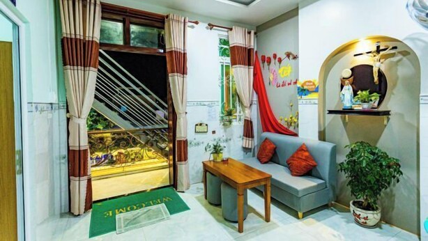 A living room with a sofa, a coffee table, a staircase, and a potted plant. - Sea Home Homestay (Phan Thiet)