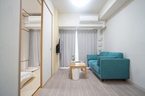 A modern hotel room with a sofa, a small table, and a wardrobe. - Shinsaibashi H2H 901 (Osaka)