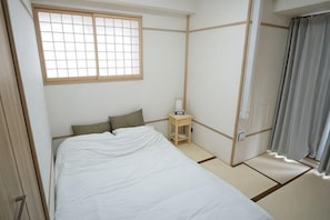 A room with a bed, a nightstand, a window, and a curtain.