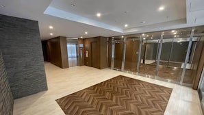 A spacious lobby with a herringbone-patterned carpet, a modern elevator, and a glass elevator door. - Shinsaibashi H2H 901 (Osaka)