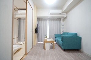 Une chambre moderne équipée d’un canapé, d’une petite table, d’une armoire et d’un appareil de climatisation.