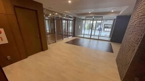 A spacious lobby with a wooden door, glass doors leading to a balcony, and a brick accent wall. - Shinsaibashi H2H 901 (Osaka)