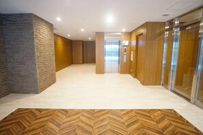 Un couloir doté d’un parquet à motifs en chevrons, de murs en bois et d’un ascenseur.