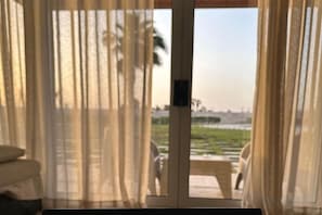 A room with a view through a glass door, featuring a bed and a chair. - Luxury Apt - Soma Bay - Hurghada -Next to Breakers (Qesm Safaga)