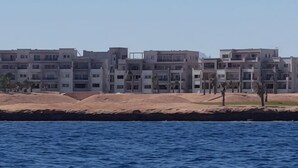 A coastal building complex with multiple floors and balconies, situated near a body of water.