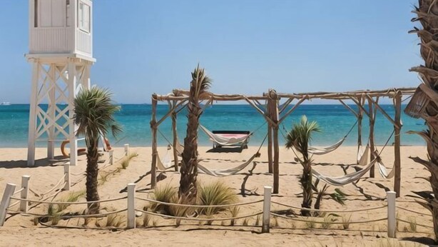 A beach with a white tower, a hammock, and a boat.