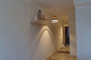 A hallway with a light fixture, a small shelf with a decorative item, and a door at the end. - Luxury Apt - Soma Bay - Hurghada -Next to Breakers (Qesm Safaga)
