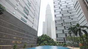 A swimming pool surrounded by high-rise buildings, with a view of a tall skyscraper in the background. - Central 2BR Apt 5 mins to KLCC Twin Towers (Kuala Lumpur)