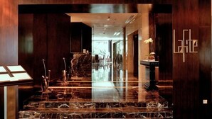 A marble-floored lobby with a reception desk, a large mirror, and a wooden wall with a logo. - Central 2BR Apt 5 mins to KLCC Twin Towers (Kuala Lumpur)