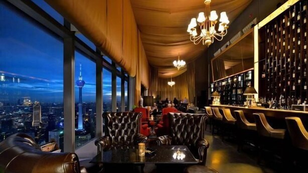 A high-rise bar with leather seating, a city view, and a chandelier. - Central 2BR Apt 5 mins to KLCC Twin Towers (Kuala Lumpur)